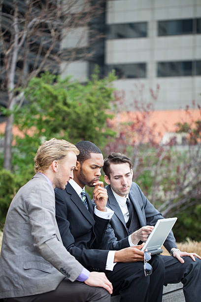istock Three serious business men considering options on laptop outdoor 180809062