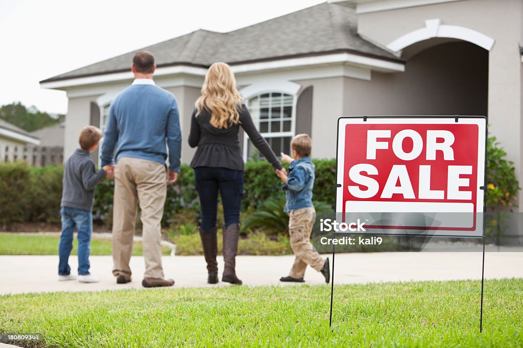 Familie, die im Haus zum Verkauf - Lizenzfrei Immobilien-Verkaufsschild Stock-Foto