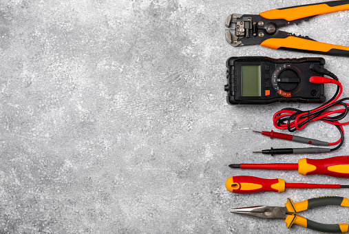 Electrician equipment on marble background with copy space.Top view.Electrician tool set.Multimeter, tester,screwdrivers,cutters,duct tape,lamps,tape measure and wires.Flet lay.