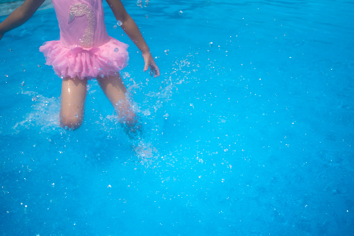 Little girl playing with water in swimming pool