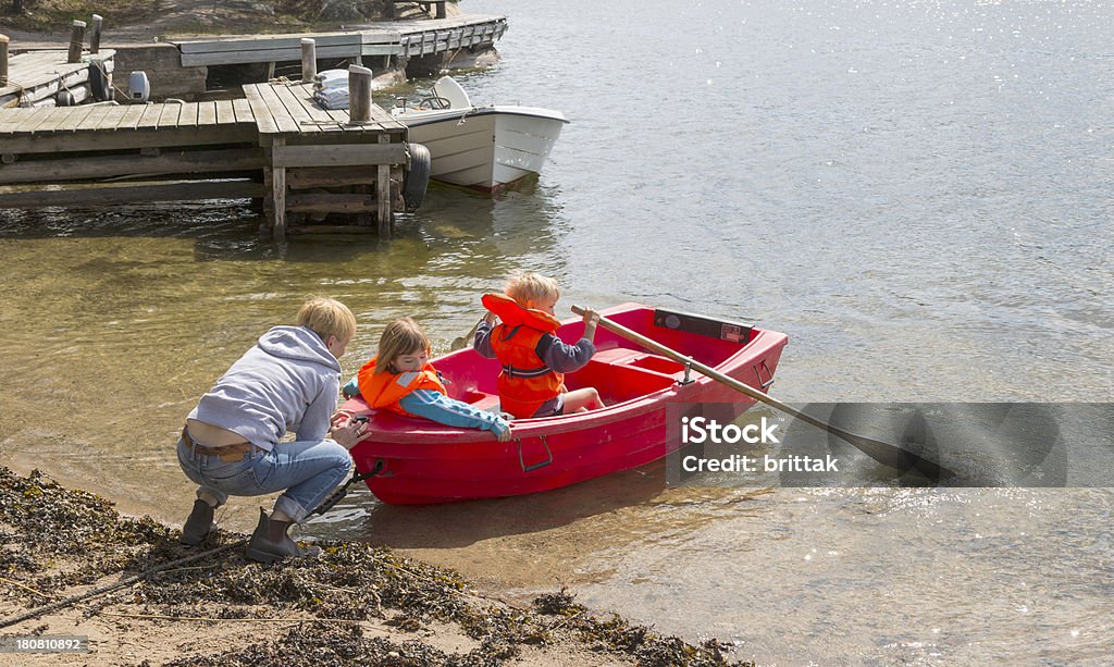 Mãe ajudando duas crianças lançamento vermelho barco a remo. - Foto de stock de 4-5 Anos royalty-free