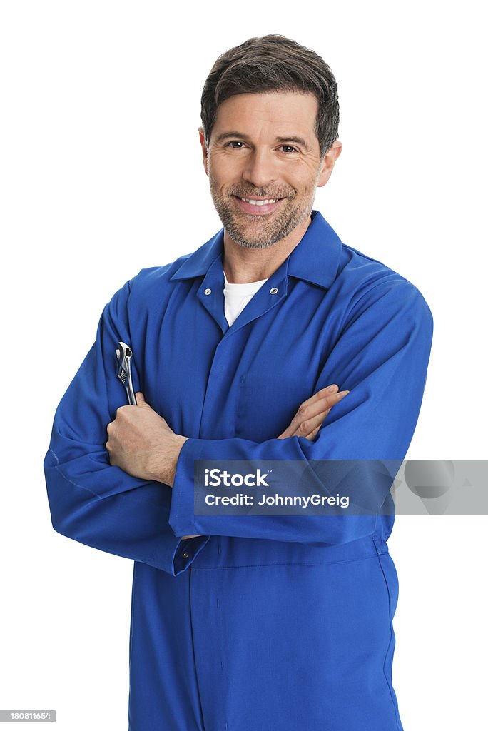 Repairman in Overalls Portrait of confident mature repairman mechanic holding wrench standing with arms crossed isolated on white background. Mechanic Stock Photo