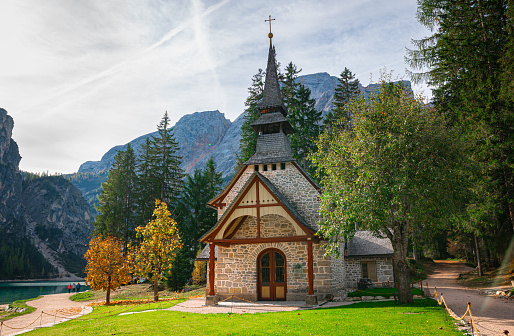 Picturesque chapel or little church on the shore of famous Braies Lake in the Dolomite Mountains.