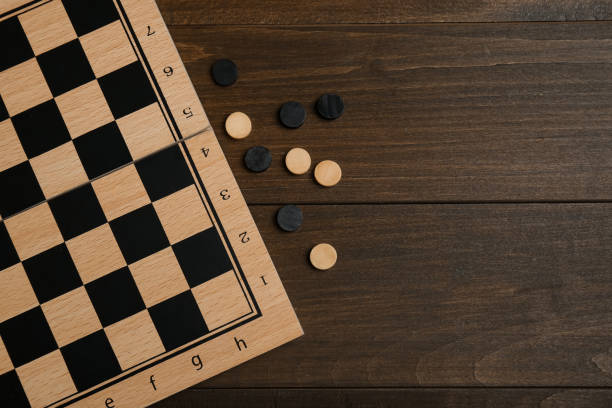 istock Checkerboard and game pieces on wooden table, flat lay. Space for text 1808120974