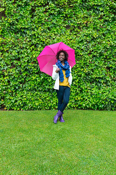 allegro giovane ragazza sotto la pioggia - candid women african descent umbrella foto e immagini stock