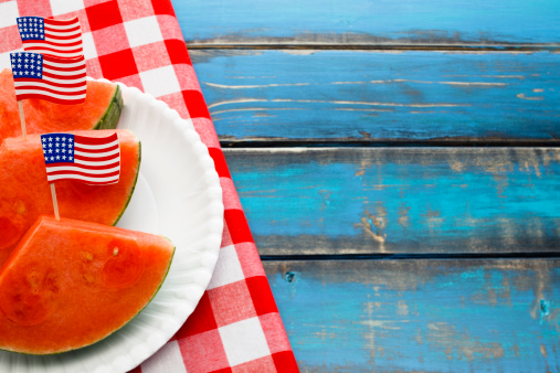 Slices of watermelon on a picnic table with traditional red checked table cloth