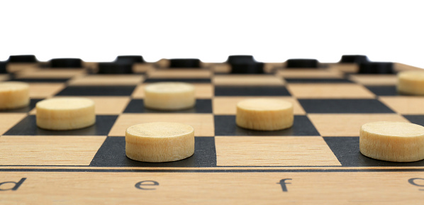 Wooden checkerboard with game pieces isolated on white, closeup
