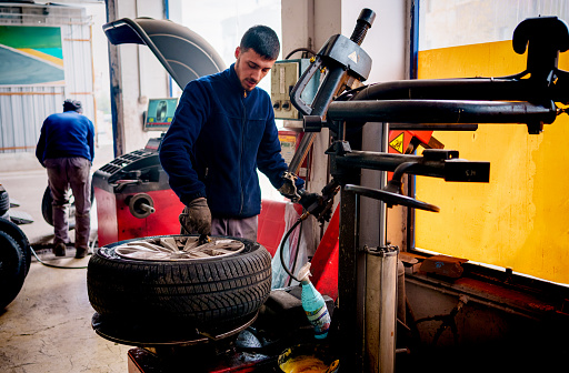 Mechanic changing tire in car service. Tire rotation machine.Car mechanic mounts tire on wheel in a workshop. tire installation in the workshop,