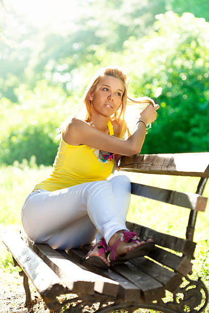 istock Beautiful young girl sitting on bench in park 180812590