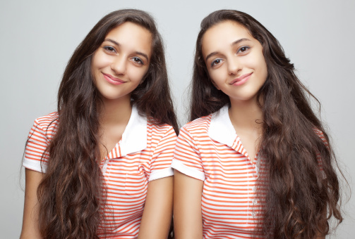 Twin teenage sisters smiling at camera