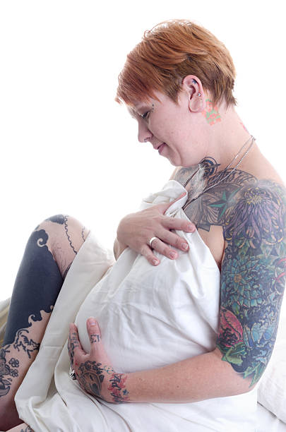 妊娠中の女性 tattooed 背ふさぎこむます。 - sheet human hand bed women ストックフォトと画像