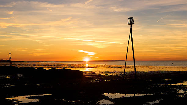 istock Tide markers at Herne Bay silhouetted on beach at sunset 180814039