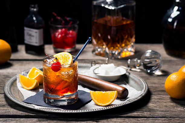 Old Fashioned Cocktail in a Vintage Bar The Old Fashioned is most commonly made by muddling sugar cubes with bitters, a cherry and an orange wedge or peel. Usually a splash of water or soda water is added along with ice, bourbon (or rye) and a garnish. maraschino cherry stock pictures, royalty-free photos & images