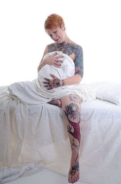 妊娠中の女性 tattooed た笑顔でベリーします。 - sheet human hand bed women ストックフォトと画像