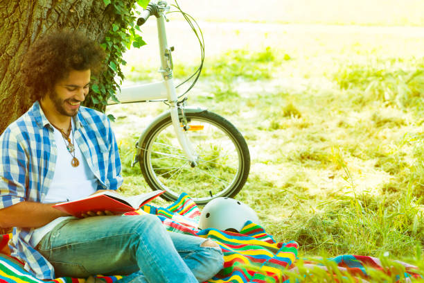istock Casual man reading in a park 180815242