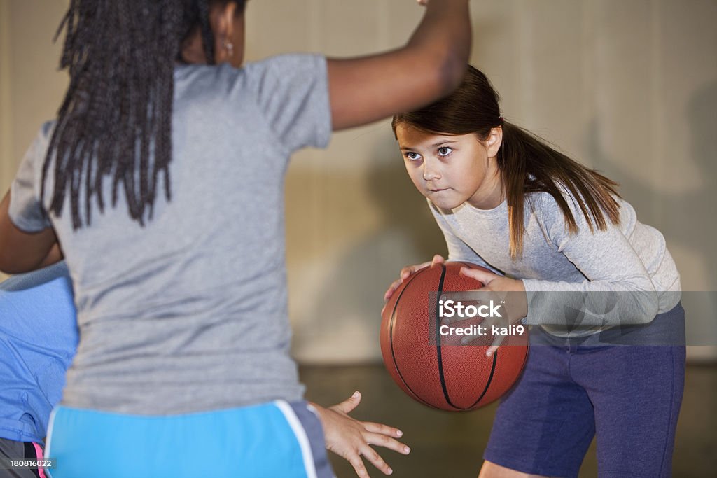 Girls playing basketball Girls (7-8 years) playing basketball in gym.  Focus on girl with ball. 6-7 Years Stock Photo