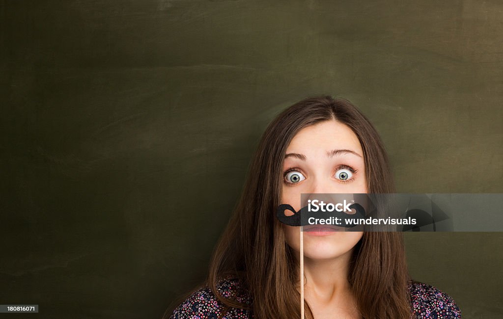 Hipster girl with mustache in front of empty blackboard. Artificial Stock Photo