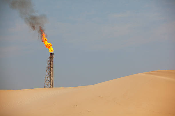 istock Oil stack fire from oil apparatus in sandy dune scenery 180816531
