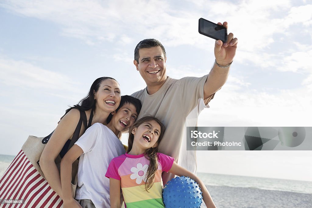 Uomo con la sua famiglia prendendo autoritratto in spiaggia - Foto stock royalty-free di Famiglia