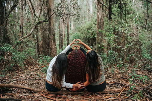 Friends making a heart with their hands behind their backs in a public park in Costa Rica
