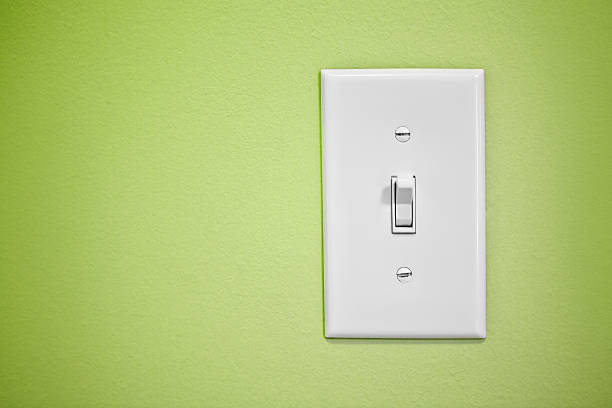 Light Switch On Green Wall A light switch on a green painted wall. light switch stock pictures, royalty-free photos & images