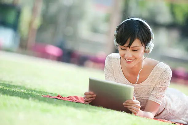 A young woman using a digital tablet in the park.