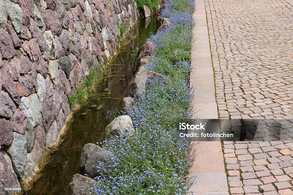 Garden watercourse Garden watercourse along a stone wall and forget-me-not flowers Forget-Me-Not Stock Photo