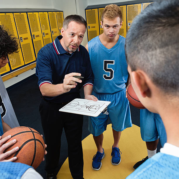 istock Coach explaining plays to basketball team in locker room 180817220