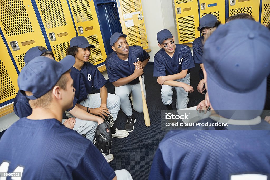 baseball lycéen équipe huddled dans un vestiaire avec entraîneur - Photo de Championnat lycéen de baseball libre de droits