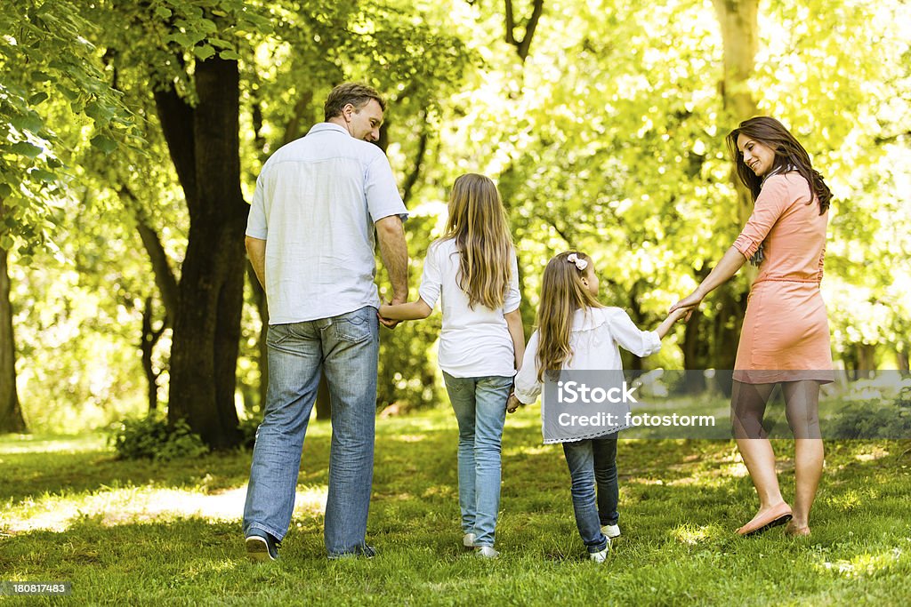 Family walking in the park Happy family of four walking together in the park. Rear view of mother, father and two daughters (age 10 and 5). Full lenght shot. 30-39 Years Stock Photo