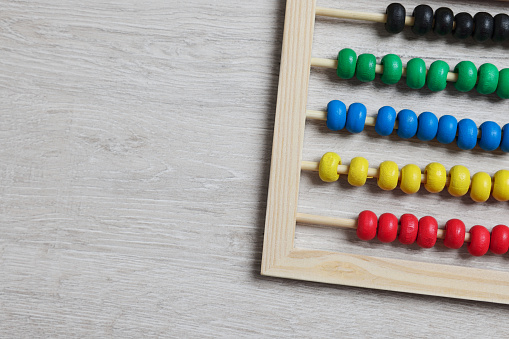 Funny math game. Colorful toy abacus on white wooden table, top view. Space for text