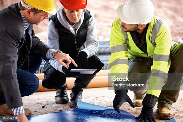 Trabajador De La Construcción Mirando Blueprints Foto de stock y más banco de imágenes de Accesorio de cabeza - Accesorio de cabeza, Adulto, Adulto joven