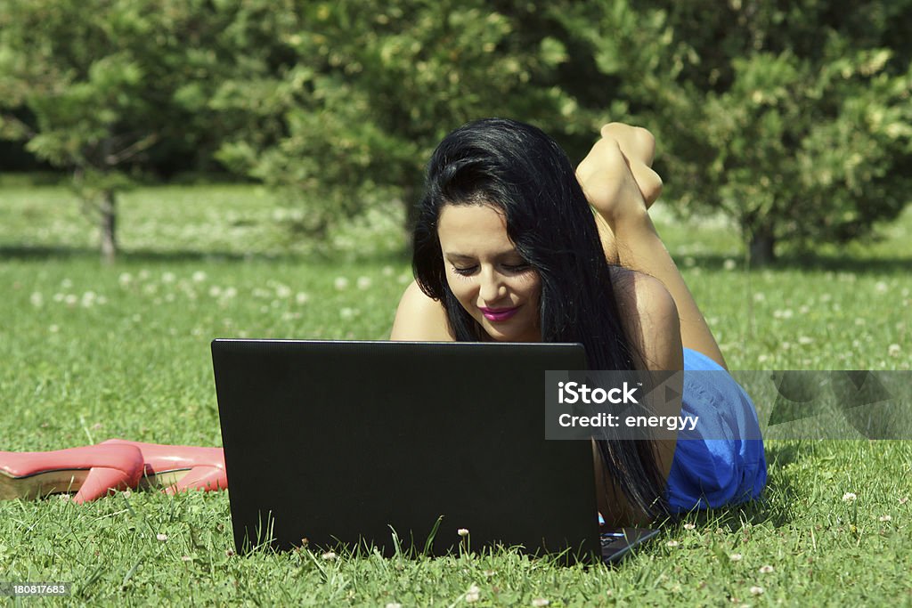 Giovane donna utilizzando il computer portatile nel parco - Foto stock royalty-free di 20-24 anni
