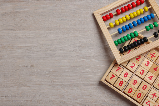Math game with numbers and colorful toy abacus on white wooden table, flat lay. Space for text