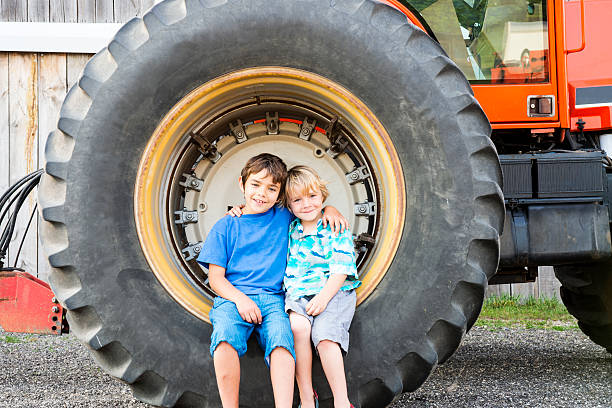 Shot of adorable little Asian baby boy holding steering wheel old tractor on the farm with copy space for your text.
