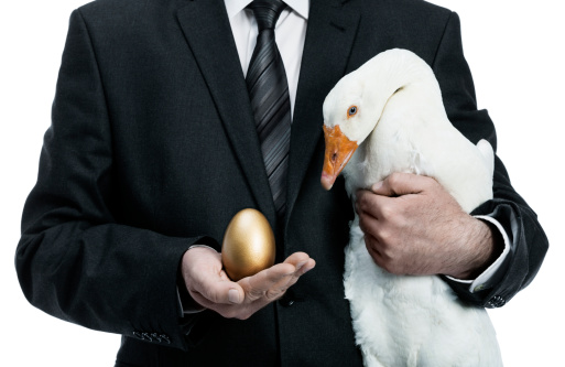 Businessman holding a goose that lays golden eggs