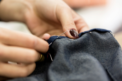 Female fashion designer sewing jeans.