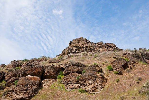 Rock Formations in Cowiche Canyon East of the Cascade Mountains, Washington’s climate is arid and the terrain is desert-like. Summertime temperatures can exceed 100 degrees Fahrenheit in regions such as the Yakima Valley and the Columbia River Plateau. This is an area of rolling hills and flatlands. During the last Ice Age, 18,000 to 13,000 years ago, floods flowed across this land, causing massive erosion and leaving carved basalt canyons, waterfalls and coulees known as the Channeled Scablands. This scene of a desert canyon was photographed from the Cowiche Canyon Trail near Yakima, Washington State, USA. jeff goulden washington state desert stock pictures, royalty-free photos & images