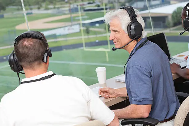 Sports reporters discussing play in press box during football game