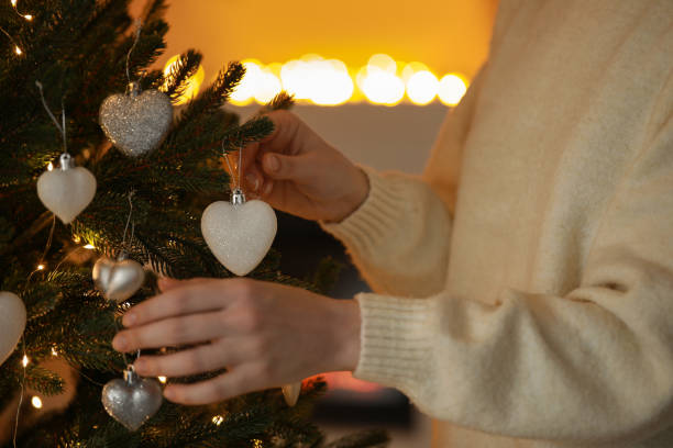 Woman decorating Christmas tree at home, closeup