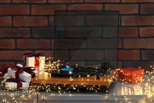 istock Turntable with vinyl record, fairy lights and Christmas gift boxes on grey table 1808197925