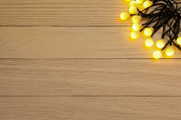 Glowing festive lights on wooden background, top view. Space for text