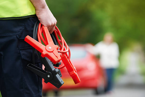 A man holding a pair of booster cable approaching a red car Coming to aid of broken down motorist jumper cable stock pictures, royalty-free photos & images