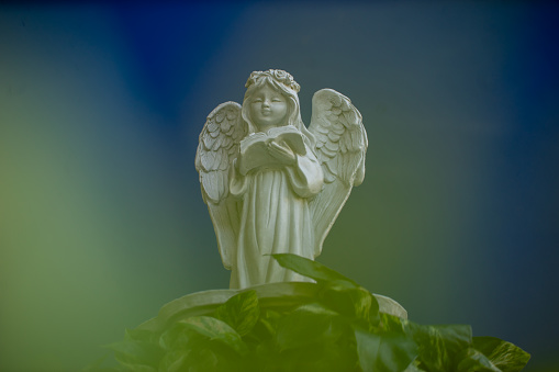 Weathered old copper angel statue with a spider web on a cemetery in Germany