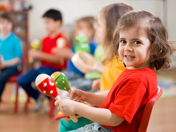 A group of preschool children in a music class.A little girl smiling at camera. 