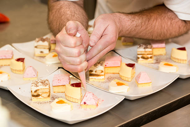 istock Baker or pastry chef is decorating desserts on plates 180821616