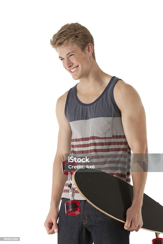 Felice giovane uomo che tiene uno skateboard - Foto stock royalty-free di Canotta