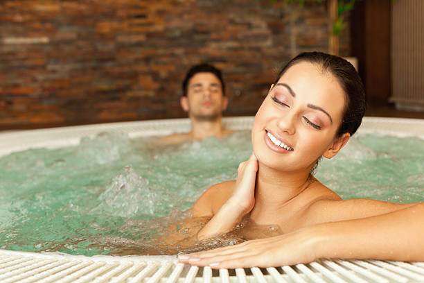 jovem casal relaxando na banheira de hidromassagem - couple hot tub spa treatment health spa - fotografias e filmes do acervo