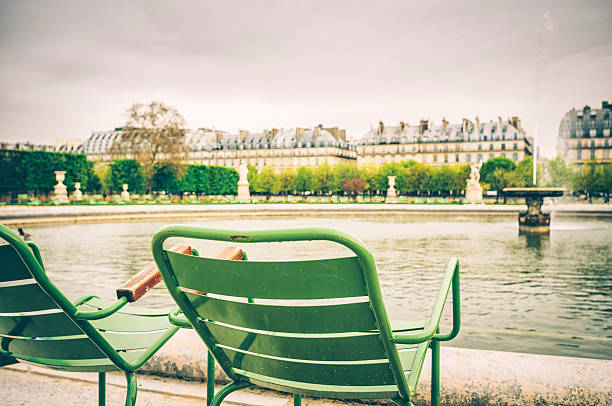 Paris, France. Monday 20 July 2020. A couple sit by a lake in the Tuileries Garden, public park in Paris.