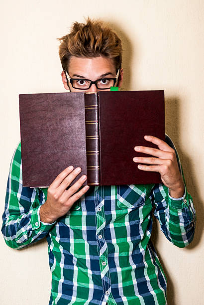 istock cute shy nerd hiding behind the book 180823426
